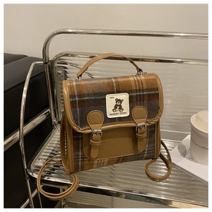 Detail of vintage plaid woolen crossbody bag featuring bear label and leather buckle straps