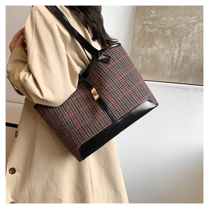 Detail view of plaid woolen tote bag with gold metal clasp and black leather trim