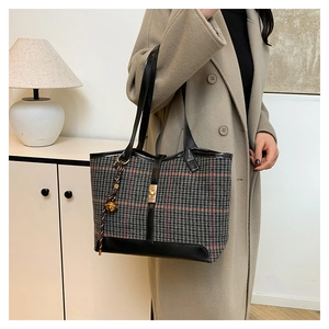 Detail of wool houndstooth tote bag featuring gold buckle and decorative bell charm