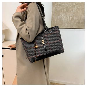 Detail of vintage houndstooth tote bag with leather straps and gold buckle charm