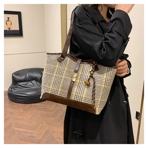 Detail of retro houndstooth pattern tote bag with leather trim and metal clasp