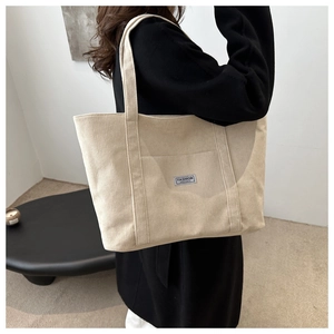 Detail der beigen Cord-Tragetasche mit gerippter Textur und modischer Logotasche