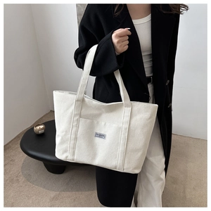 Detailansicht der Cord-Struktur und des blauen Mode-Labels an der großen Tragetasche