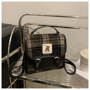 Detailed view of British plaid backpack with a cute bear patch and leather accents