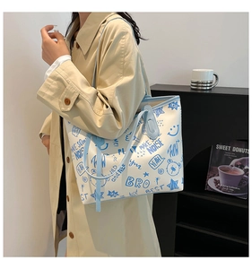 Detail view of large graffiti tote bag with light blue straps and urban printed patterns