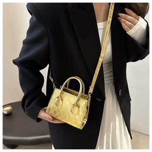 Mini borsa a mano dorata in pelle verniciata trapuntata con blazer nero e vestito