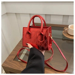 Dettaglio borsa trapuntata in pelle verniciata rossa con finiture metalliche dorate