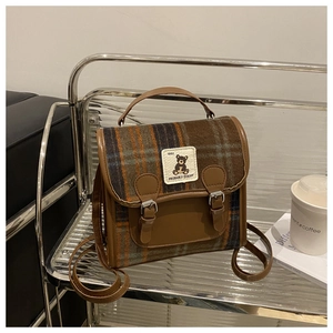 Detail of vintage plaid backpack with bear embroidery patch and brown leather straps