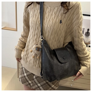 Dettaglio della borsa hobo nera con un grazioso ciondolo in peluche di alpaca marrone