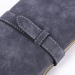Detailed close-up of matte dark blue wallet texture with white stitching and gold zipper