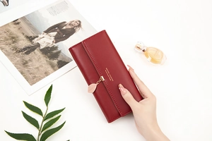 Detail of red PU leather tri-fold wallet featuring a gold leaf pendant and metal logo