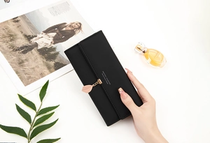 Detailed view of women's long black PU leather wallet with a gold leaf pendant detail