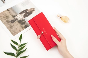 Detail of red PU leather long wallet with gold leaf pendant and snap closure