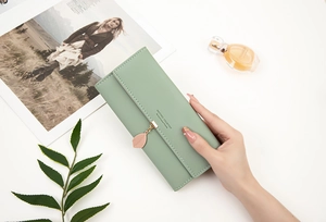 Close-up of light green PU leather wallet featuring leaf pendant and stylish lettering