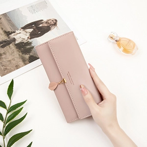 Detailed view of long pink PU leather wallet featuring a gold leaf pendant and snap closure