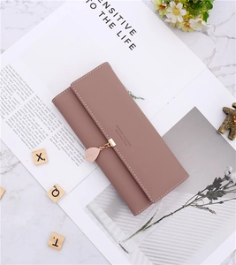 Detail of mauve faux leather long wallet with leaf pendant and magnetic closure on marble
