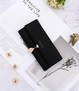 Detail of a black long purse featuring a matte leather finish and pink leaf charm