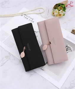 Detail of long tri-fold wallets in black and pink with elegant leaf pendant charm