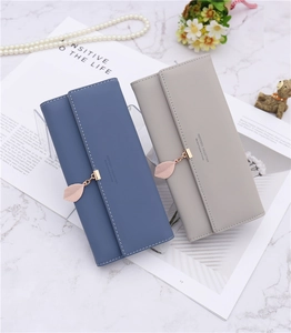 Detail showing leaf pendant and stitching on blue and taupe long wallets for women