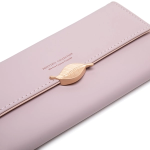 Macro detail of faux leather women wallet with golden leaf pendant and engraved text