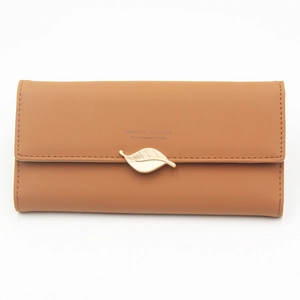 Detail view of tan faux leather long wallet with golden leaf pendant and flap closure