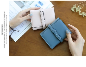 Close-up of elegant leather wallets in pink and blue on a rustic wooden desk