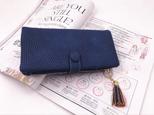 Dettaglio del portafoglio lungo blu navy con trama litchi, nappa e zip dorata in primo piano