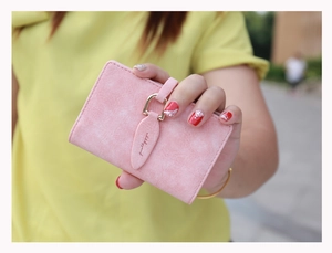 Detail of pink matte suede wallet with gold ring buckle and leaf-shaped decorative strap