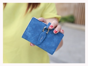 Detail of blue matte leather card holder with leaf buckle and gold ring closure