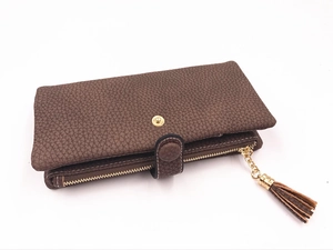 Dettaglio portafoglio in pelle marrone con grana litchi, zip dorata e nappa decorativa
