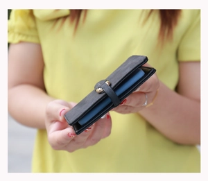 Close-up of black matte leather card holder with leaf buckle and blue multi-card slots
