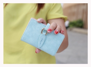 Close-up of light blue matte card holder with metal buckle and delicate stitching