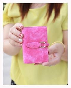 Detail of rose pink matte leather card holder featuring gold U-shaped buckle and leaf strap