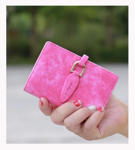 Pink frosted leather card holder with gold U-shaped buckle held by a model outdoors