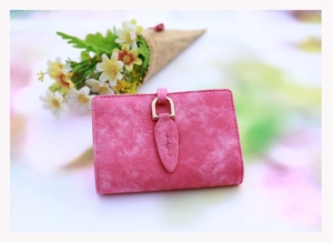 Detailed macro view of pink frosted leather wallet featuring gold U-shaped leaf buckle