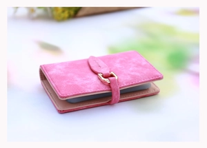 Close-up of rose pink matte leather card holder with gold buckle and leaf snap detail