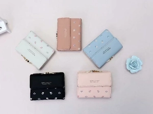 Flat lay of multiple floral PU leather tri-fold wallets with metal clasp in various colors