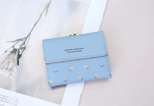 Detail of light blue floral faux leather wallet with vintage gold clasp on magazine