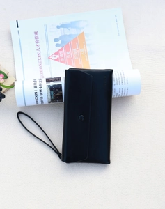 Close-up of black leather long wallet with wristlet strap and magnetic snap closure