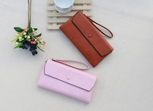 Flat lay of pink and brown leather wallets with wristlets on a textured background