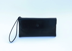 Close-up of black leather clutch bag with snap closure, logo detail and wristlet strap