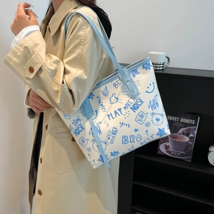 Large graffiti print tote bag in white and blue featuring trendy illustrations and lettering