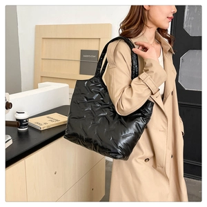 Détail du sac cabas matelassé noir en nylon brillant porté à l'épaule pour femme