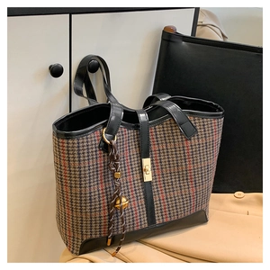 Detail of houndcheck tote bag featuring golden twist lock and braided rope pendant