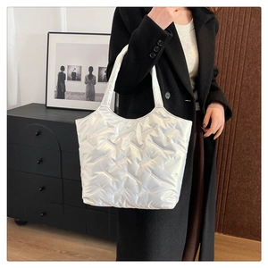 Sac fourre-tout matelassé blanc brillant porté à l'épaule dans un cadre élégant et chic