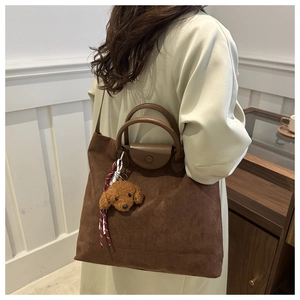 Dettaglio della borsa tote in pelle scamosciata con manici in pelle e charm a orsetto