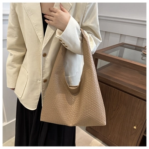 Sac fourre-tout beige tressé avec bandoulière large, porté avec un blazer en velours côtelé
