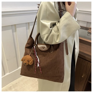 Dettaglio di una grande borsa tote in pelle scamosciata marrone con un ciondolo a orsetto