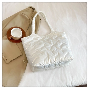 Gros plan du sac cabas matelassé blanc brillant avec texture douce et finition élégante