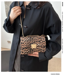 Detail einer Schultertasche mit Leopardenmuster, Goldschließe und Metallkettenriemen